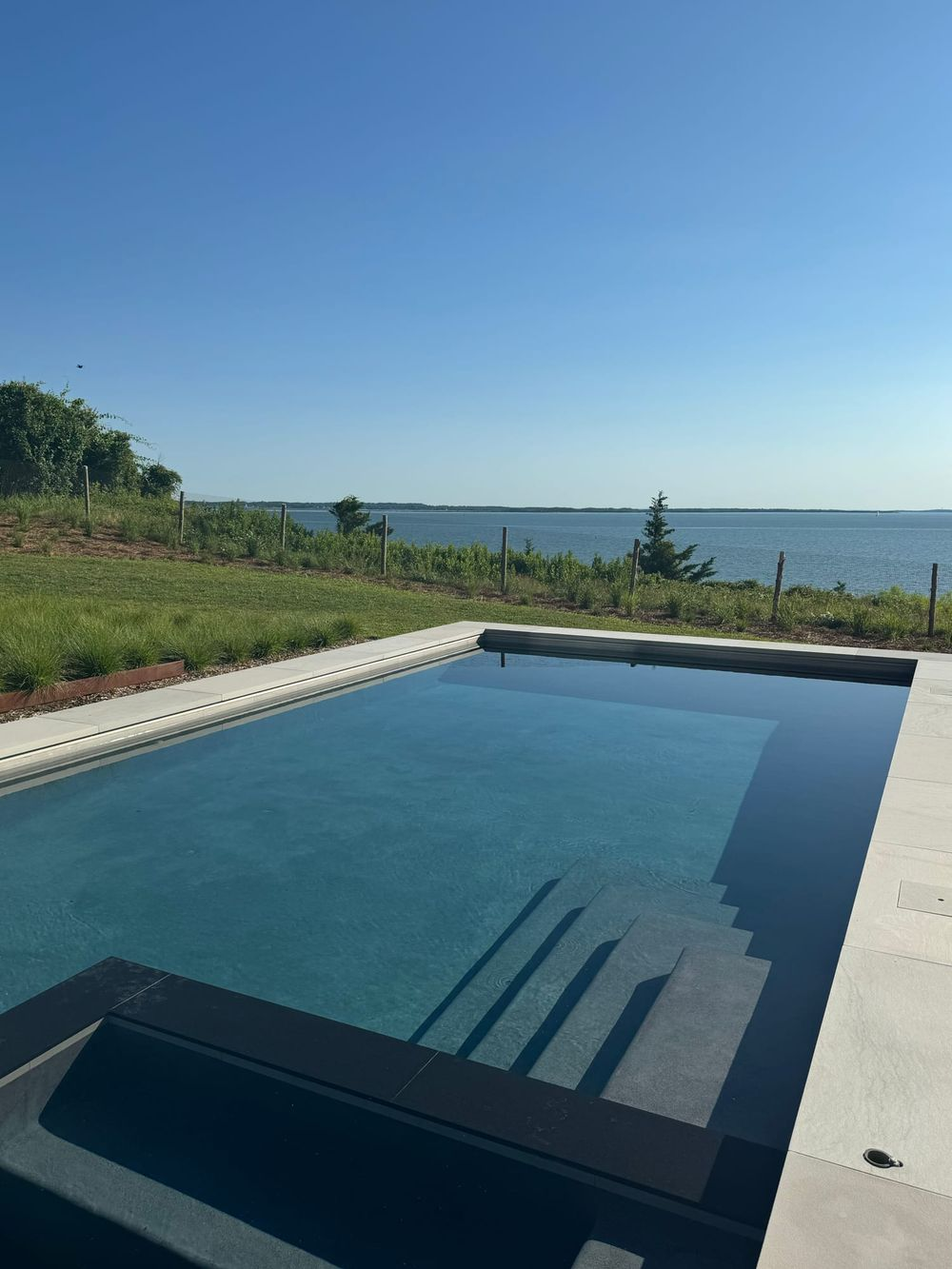 Waterfront swimming pool with wide entry steps overlooking the bay